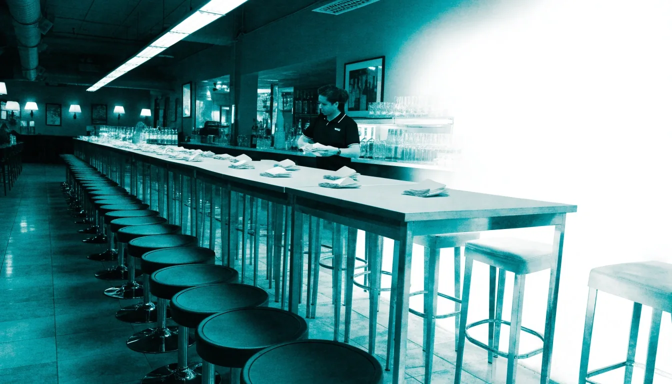Empty sports-bar stools and a server setting a high-top table short of the kickoff rush